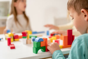 Kindergarten children playing with colorful building blocks. Hea